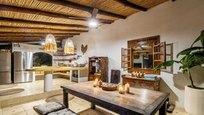 A spacious kitchen with modern appliances, a wooden dining table with candles, and a large mirror. - Bungalow Pacifico - Beach Chic! (North Santa Teresa)