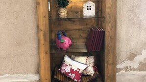 A wooden shelf with various decorative items including a cactus, a piggy bank, and a small house model. - Lovely 1-Bedroom Adobe Escape (Mesilla)