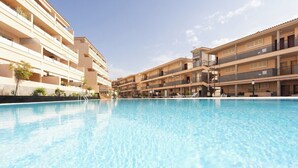 A swimming pool with a clear blue surface, surrounded by multi-story buildings with balconies and a flat roof. - Home2Book Cozy Apartment Los Cristianos, Wifi&Pool (Los Cristianos)