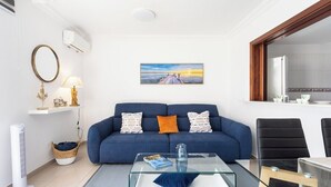 A modern living room with a blue sofa, a glass coffee table, and a painting on the wall. - Home2Book Cozy Apartment Los Cristianos, Wifi&Pool (Los Cristianos)