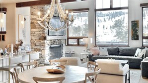 A spacious kitchen with a stone fireplace, wooden dining table, and modern appliances.