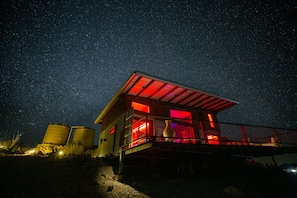 Un edificio con un balcone illuminato di rosso e un vaso grande sul ponte.