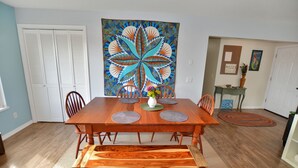 A dining area with a wooden table, chairs, a bench, and a large decorative painting on the wall. - Atargatis "the first mermaid"; an updated & spacious home, close to everything! (Brookings)