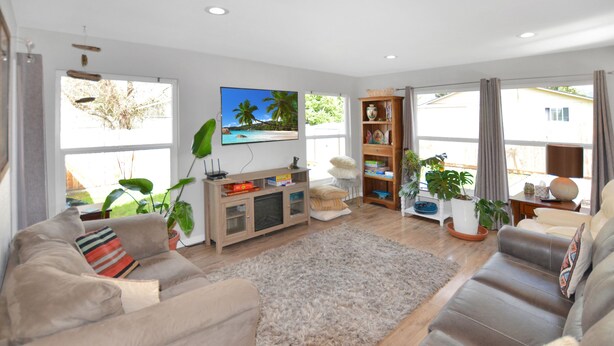 A spacious living room with a large flat-screen TV, a wooden entertainment unit, a beige sofa, a brown leather sofa, and a shaggy rug. - Atargatis "the first mermaid"; an updated & spacious home, close to everything! (Brookings)