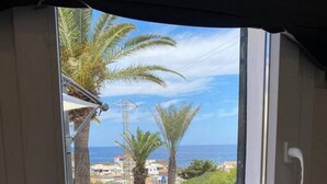 Une cuisine avec une fenêtre donnant sur une zone côtière, offrant une vue sur la mer et les voitures garées.