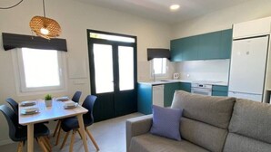 Un espace de vie compact comprenant un coin repas, une kitchenette et un canapé.