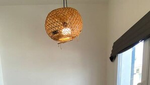 Un coin repas avec un luminaire rond en fibres tressées suspendu au-dessus d’une table rectangulaire dressée pour quatre personnes.