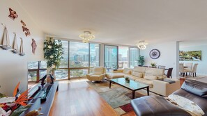 A spacious living room with a large window offering a city view, a sofa set, a coffee table, and decorative items.