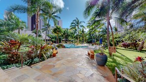Relax by the pool surrounded by lush tropical plants and palm trees.