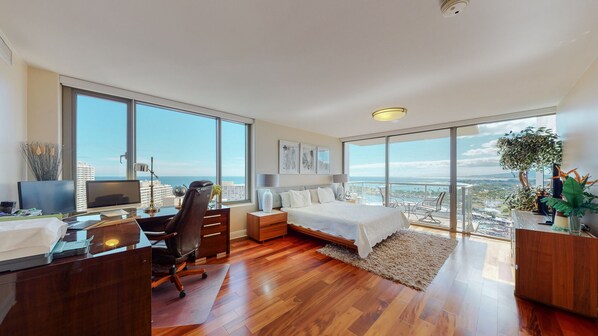 Enjoy expansive city and ocean views from this high-rise room, featuring a large bed, desk, and seating area.