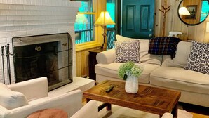Una sala de estar acogedora con chimenea, un conjunto de sofás, una mesa de centro y un espejo.
