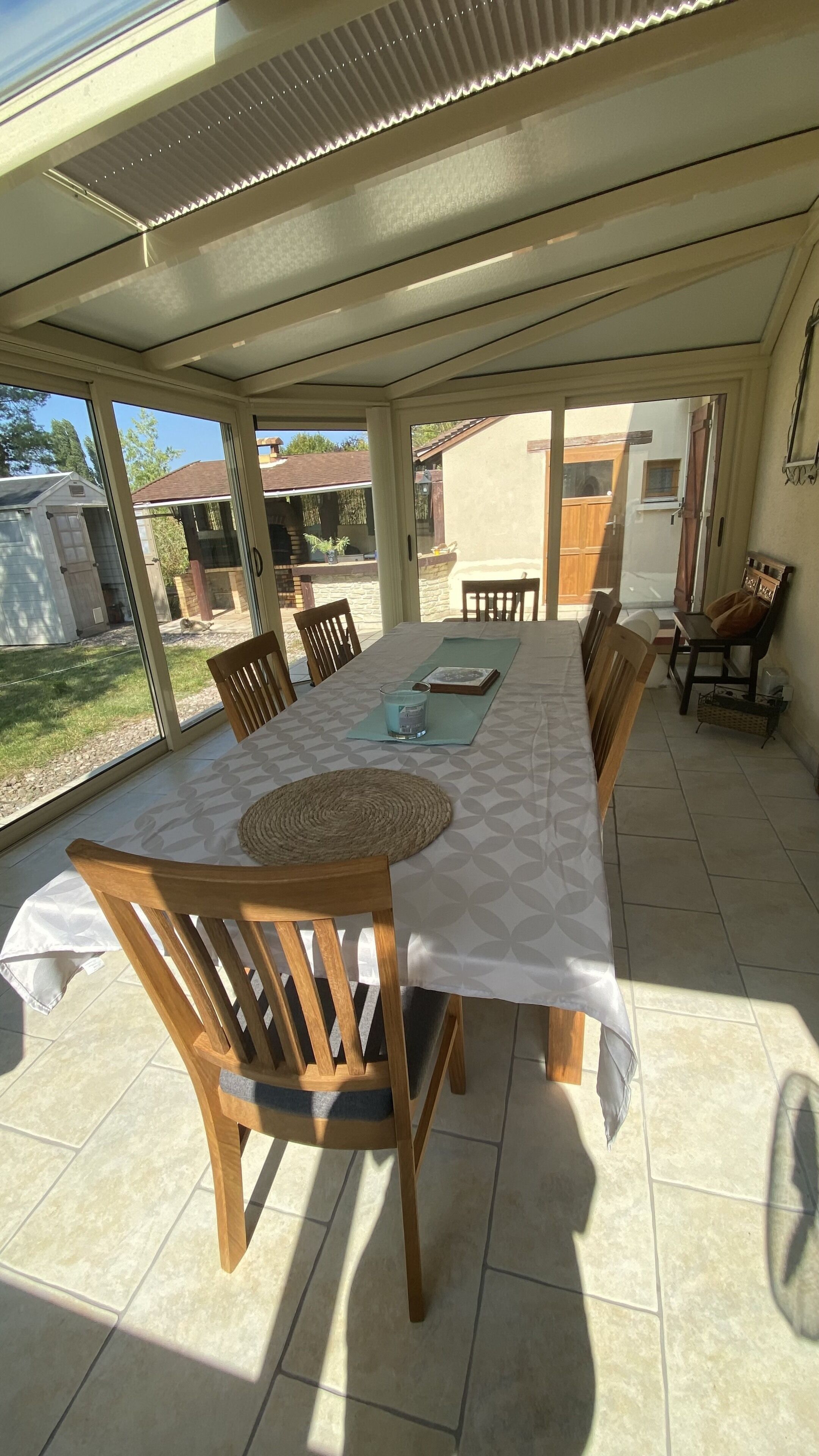 Een overdekt terras met een eettafel voor zes personen, omringd door houten stoelen.
