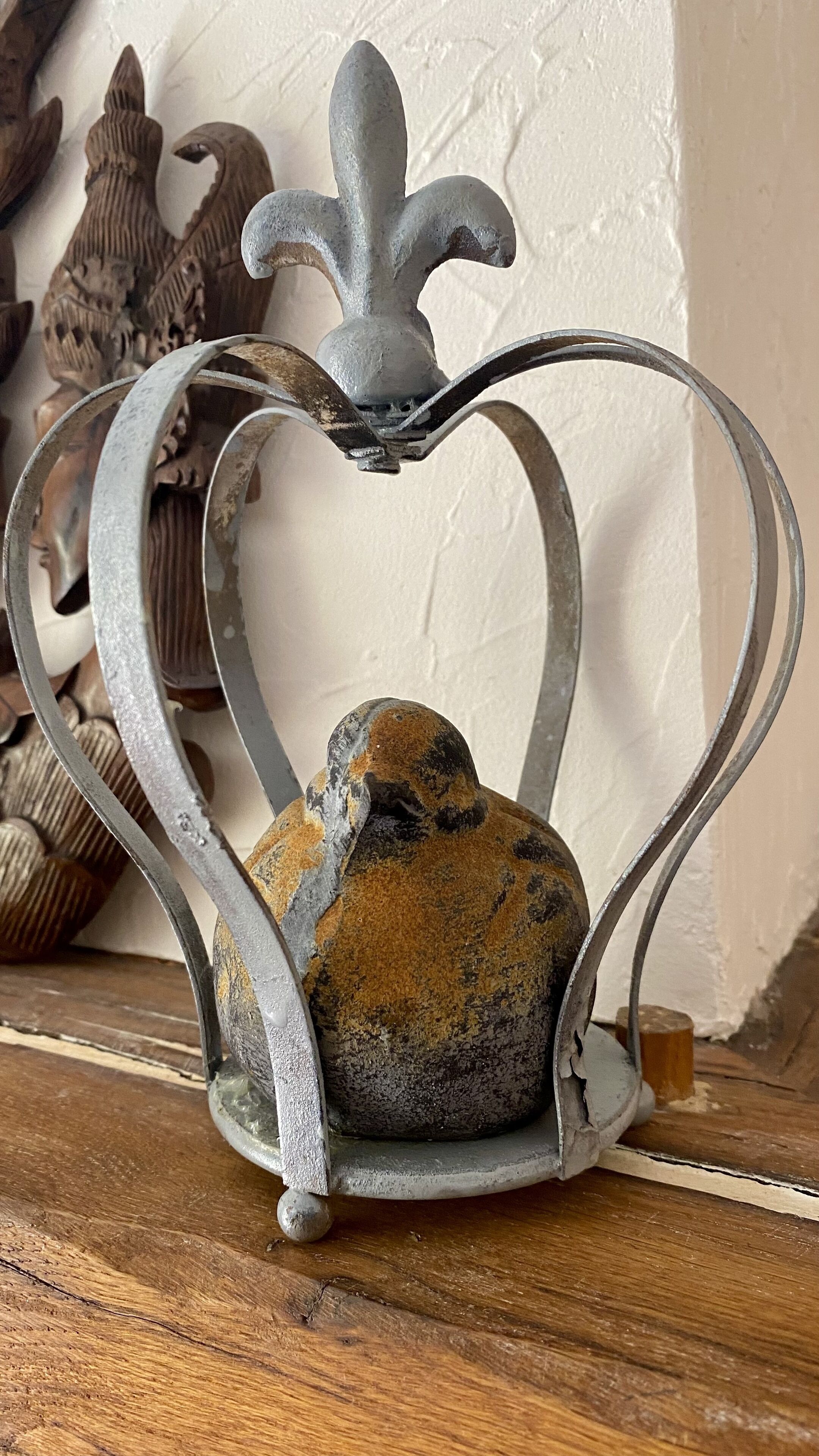 A decorative metal heart-shaped object with a crown design, placed on a wooden surface.