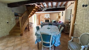 A dining area with a round table, chairs, and a staircase leading to another room. - The Nebula (notre dame de l'isle)