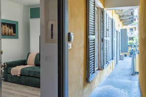 A narrow corridor with a green sofa and a bed in a room. - Studio 14, comfortable apartment with air conditioning and Wi-Fi, 100 meters from the Buonarroti metro station on the red line - By Guestaly (Milano)