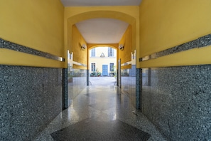 A corridor with a tiled floor and yellow walls, leading to a building with a visible window and door. - Studio 14, comfortable apartment with air conditioning and Wi-Fi, 100 meters from the Buonarroti metro station on the red line - By Guestaly (Milano)