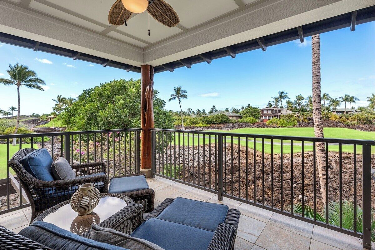 A covered outdoor seating area with wicker furniture and a view of a golf course.