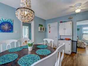A dining area with a wooden table, white chairs, and teal placemats. - Steps to South Beach, Heated Pool Access (Tybee Island)