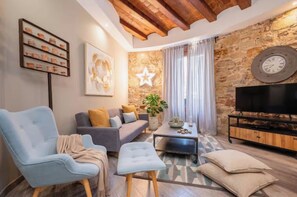 Una sala de estar con sofá, sillones, una mesita de centro, televisor, un reloj y decoración con estrellas en la pared.