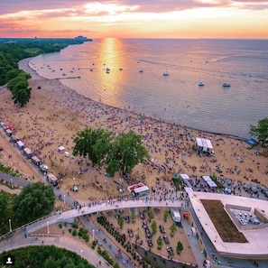 An aerial view of a beach with a large crowd, boats, and a sunset. - STUNNING LUXURY BEACH HOUSE (Cleveland)