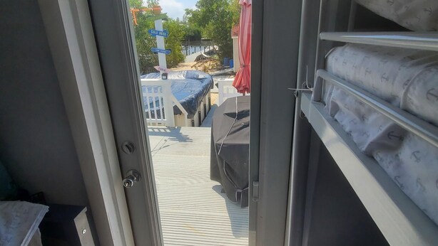 Una stanza con una porta scorrevole che dà su uno spazio all'aperto. All'interno, scaffali portaoggetti e un letto con materasso decorato.