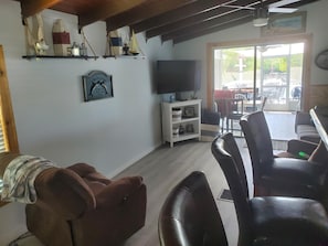 Un salon équipé d’un téléviseur, décoré avec un modèle de voilier, et comprenant un coin repas avec des chaises et une table.