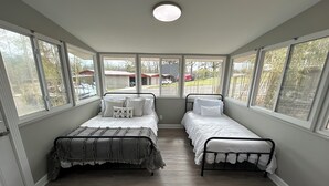 Ein Zimmer mit zwei Betten, großen Fenstern und einer Deckenleuchte.