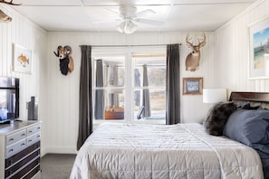 Un dormitorio con cama, cómoda, televisor y dos venados montados en la pared.