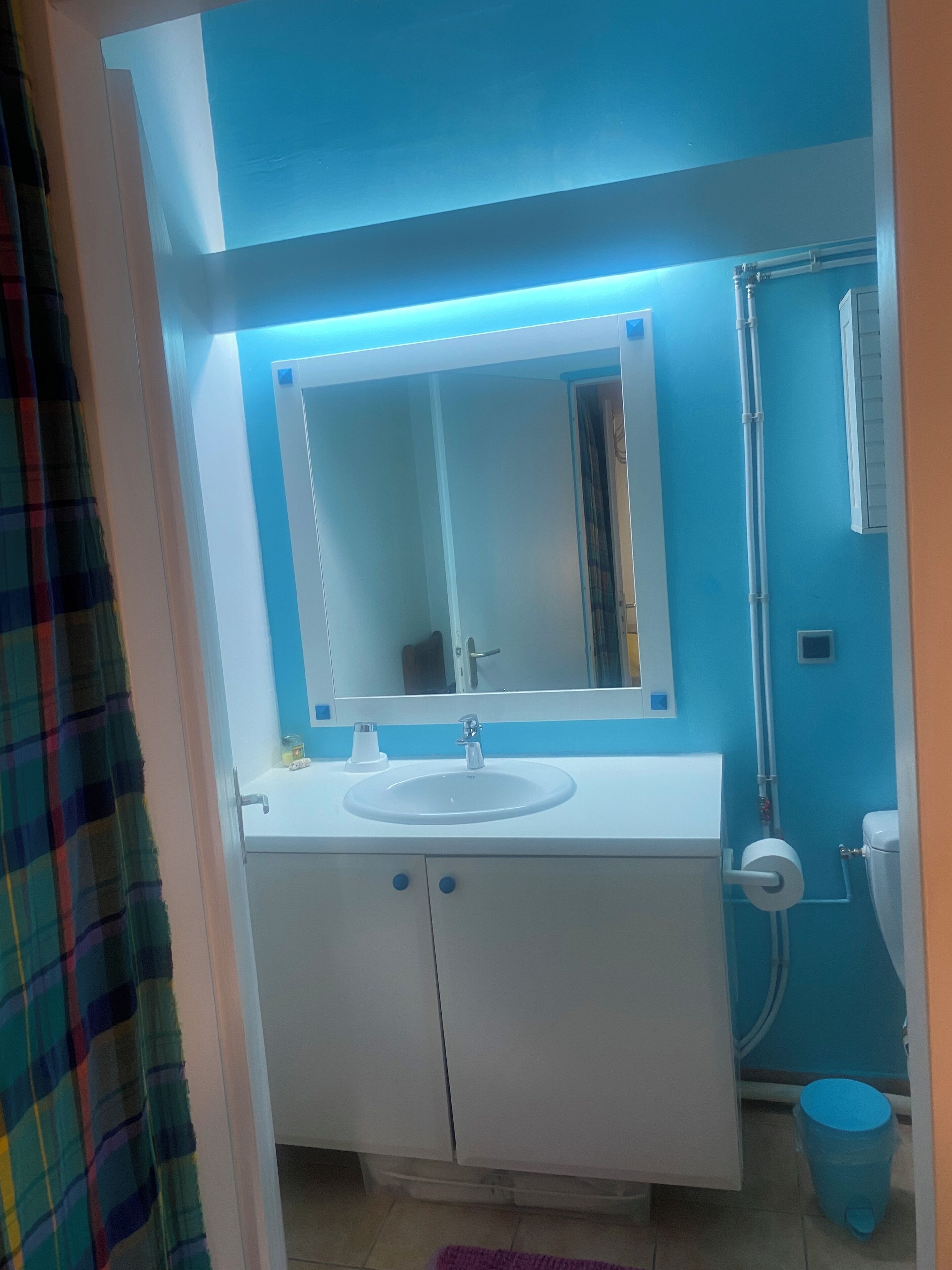 A bathroom with a white sink, a mirror, and a shower.
