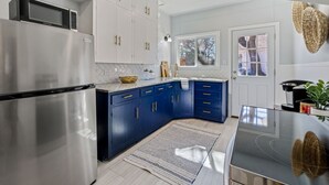 A modern kitchen with stainless steel appliances, blue cabinets, and a herringbone tile backsplash. - Quaint and Cozy Historic Home in Downtown Weatherford (Weatherford)