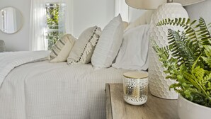 A neatly arranged bedroom with a bed, pillows, a lamp, and a potted plant. - Quaint and Cozy Historic Home in Downtown Weatherford (Weatherford)