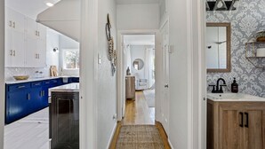 A kitchen with blue cabinets, a black refrigerator, and a wooden floor. - Quaint and Cozy Historic Home in Downtown Weatherford (Weatherford)