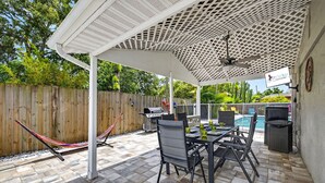 Una terrazza esterna con zona salotto coperta, piscina e barbecue.