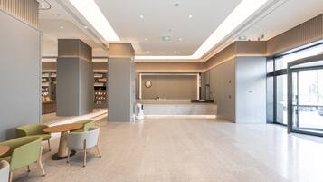 A modern lobby with a reception desk, seating area, and bookshelves.