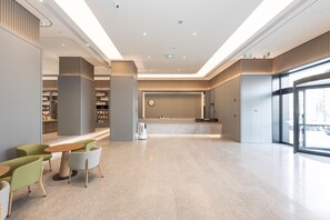 A modern lobby with a reception desk, seating area, and bookshelves.