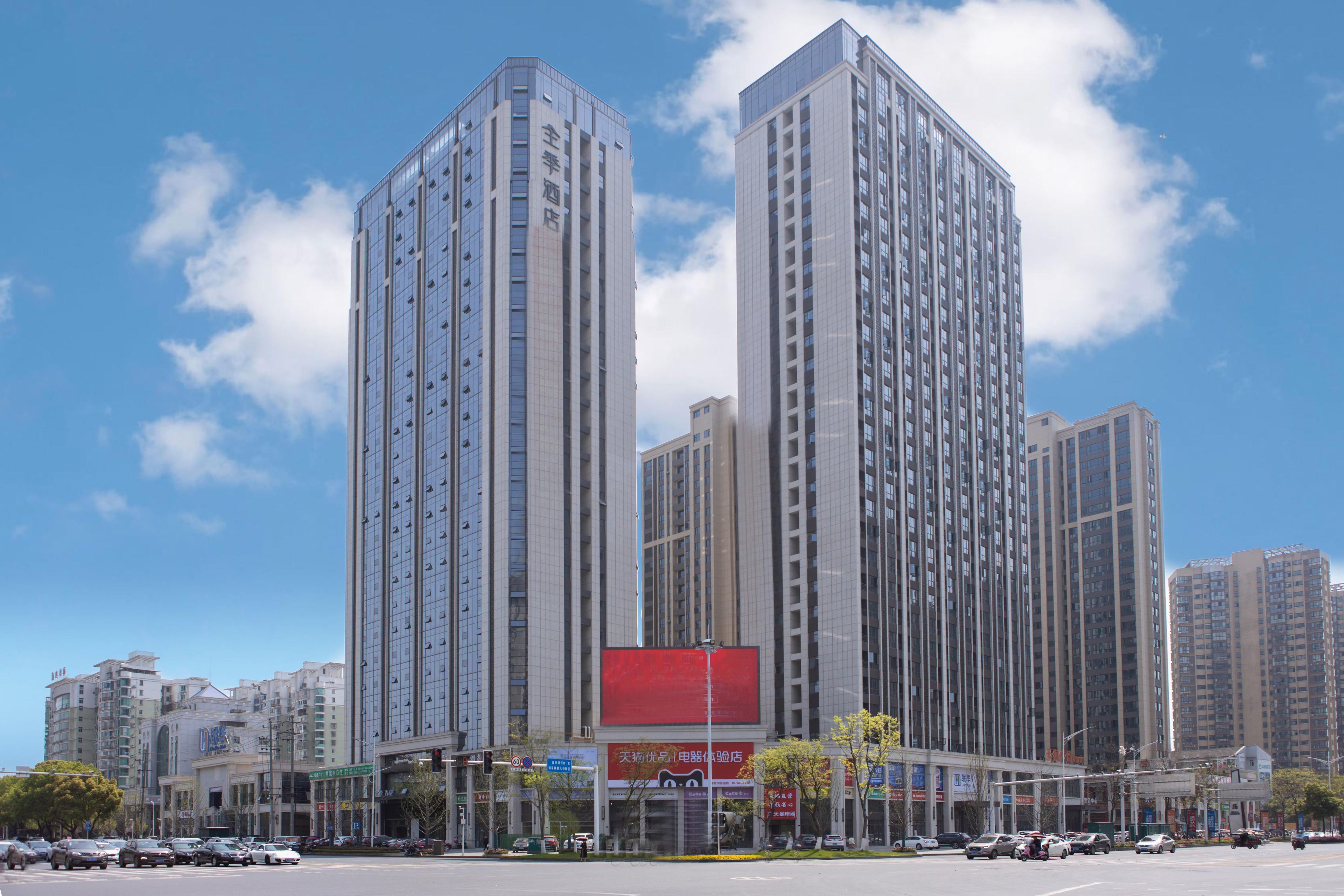 A high-rise building with multiple floors, large windows, and a prominent red advertisement on the facade.