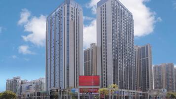 A high-rise building with multiple floors, large windows, and a prominent red advertisement on the facade.