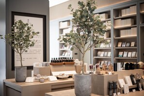 A modern interior with two potted plants, a reception desk, and shelves with various items.