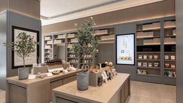 A modern interior with a reception desk, shelves with books, and decorative plants.