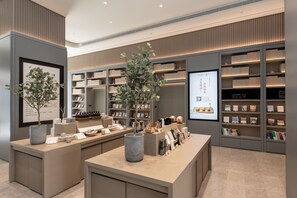 A modern interior with a reception desk, potted plants, and bookshelves.