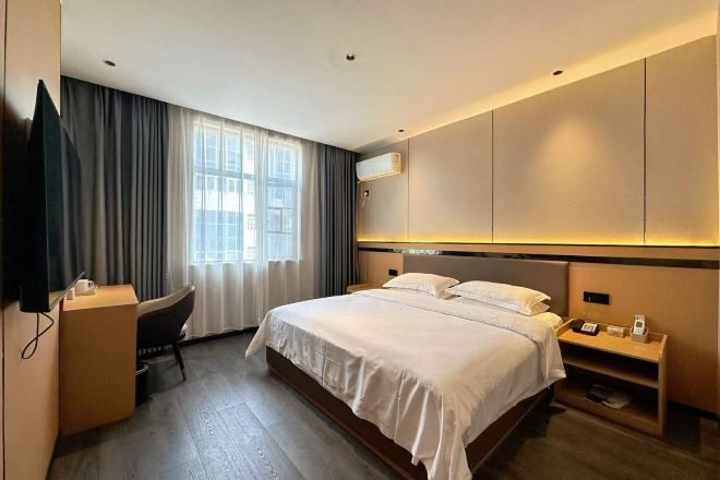 A modern hotel room with a large bed, a desk, and a television.