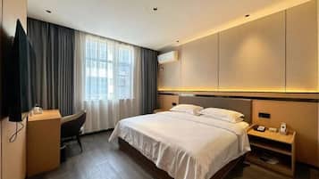 A modern hotel room with a large bed, a desk, and a television.