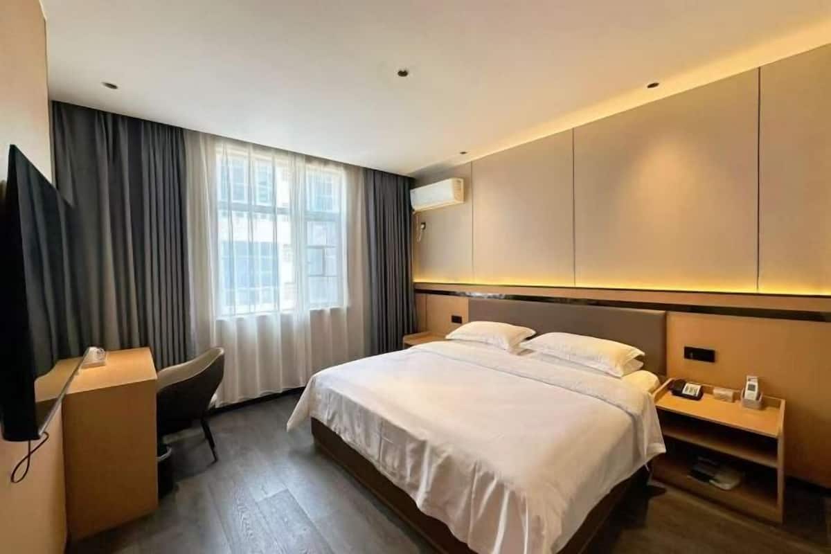 Una habitación de hotel moderna con una cama grande, un escritorio, una silla y un televisor.