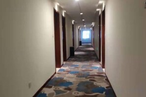 A hotel hallway with a carpeted floor, doors on both sides, and a light source at the end. - Xiya Zhenpin Hotel (Xinyu)