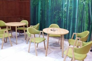 Una habitación con mesas redondas y sillas verdes dispuestas alrededor.