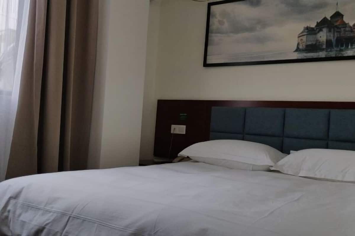 Habitación de hotel con una cama grande, un cabecero y un cuadro de un castillo en la pared.