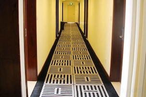 A hallway with a patterned floor leading to a door at the end.