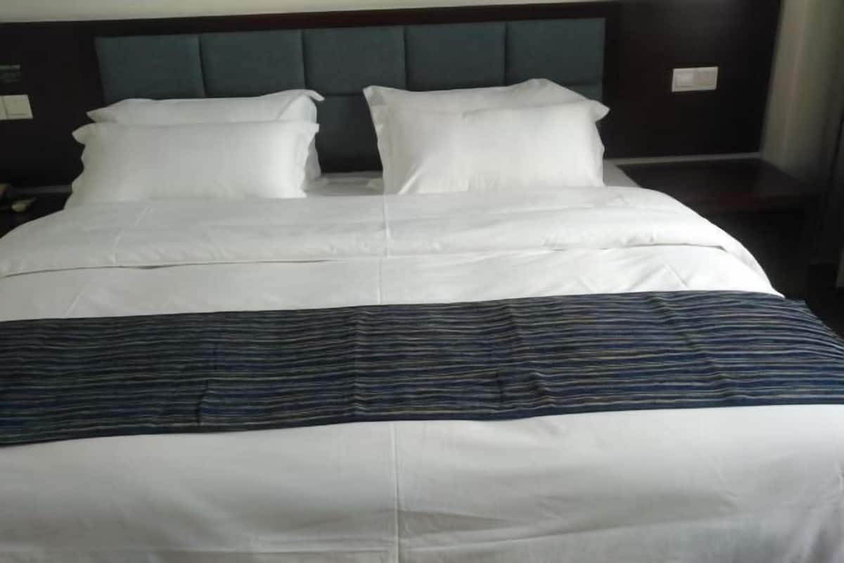 Una cama bien hecha con ropa blanca y una manta a rayas.