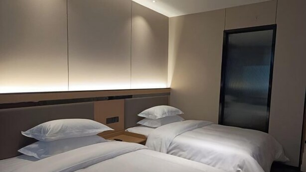 Una habitación de hotel con dos camas, una mesita de noche de madera y un espejo grande.