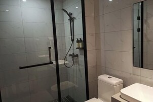 Un baño moderno con ducha de vidrio, inodoro y lavamanos.